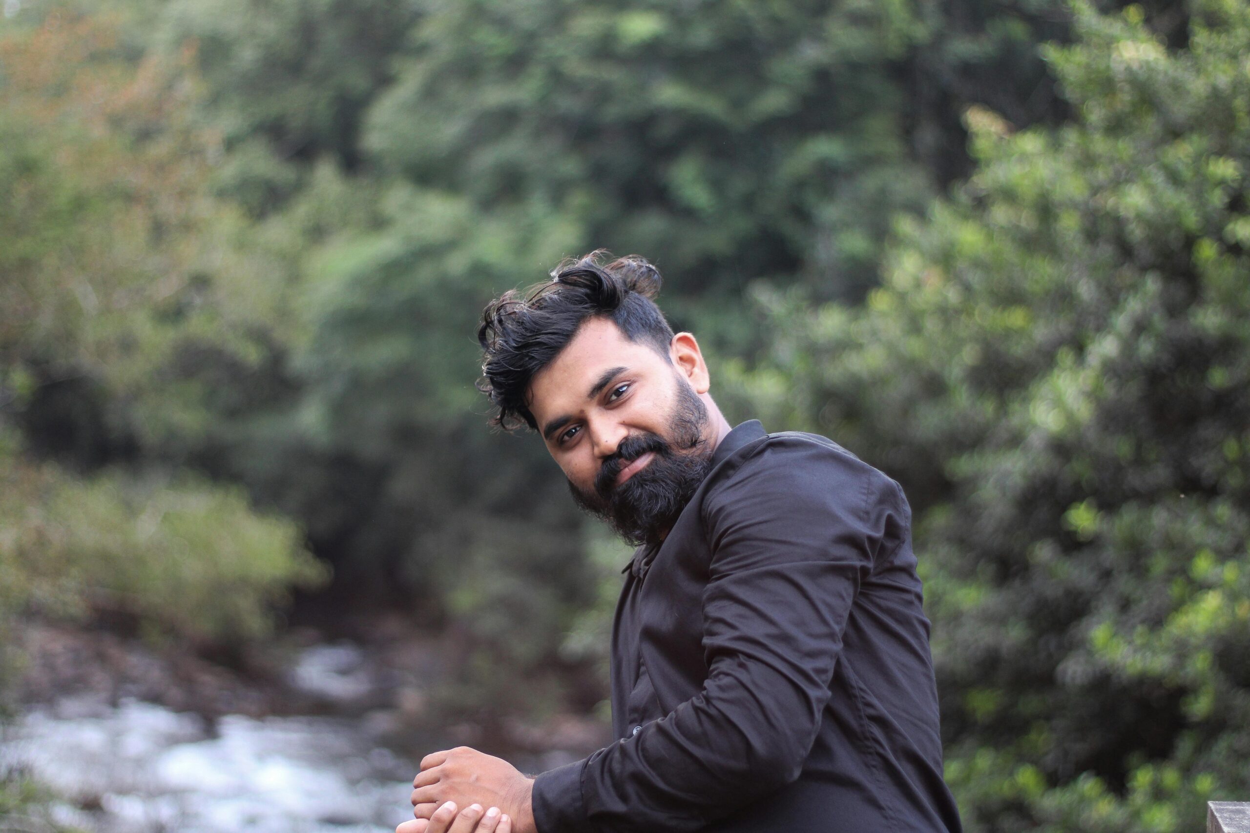 pexels-photo-28772241-28772241 Portrait of an Indian man wearing a black shirt by a lush riverside in Nilambur, Kerala.